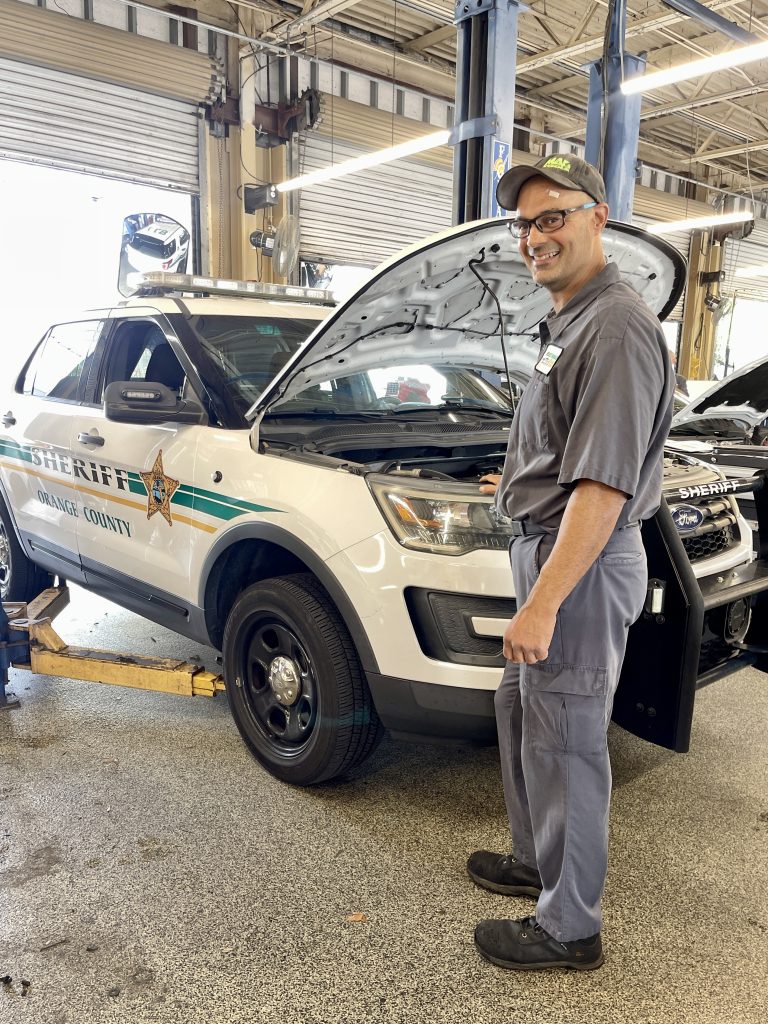Fleet Technician posed in front of a car with an open hood