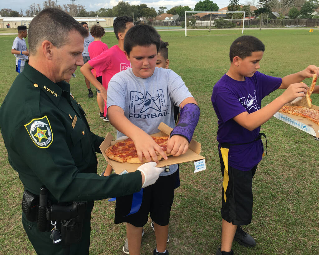Sheriff Mina serving pizza to children