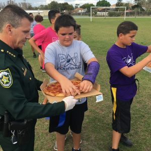 Sheriff Mina serving pizza to children