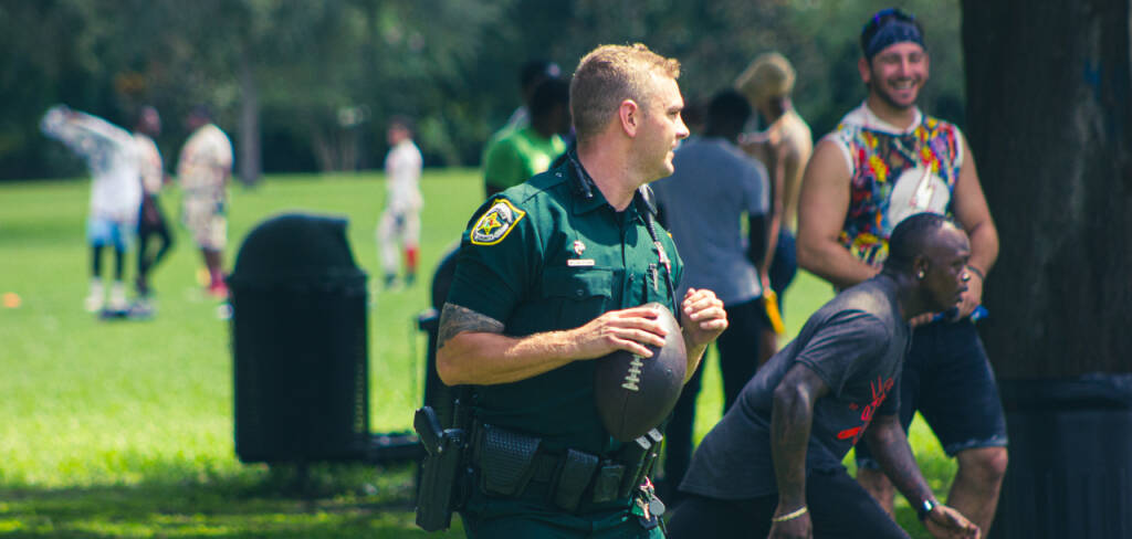 deputy playing football at a park with civilians