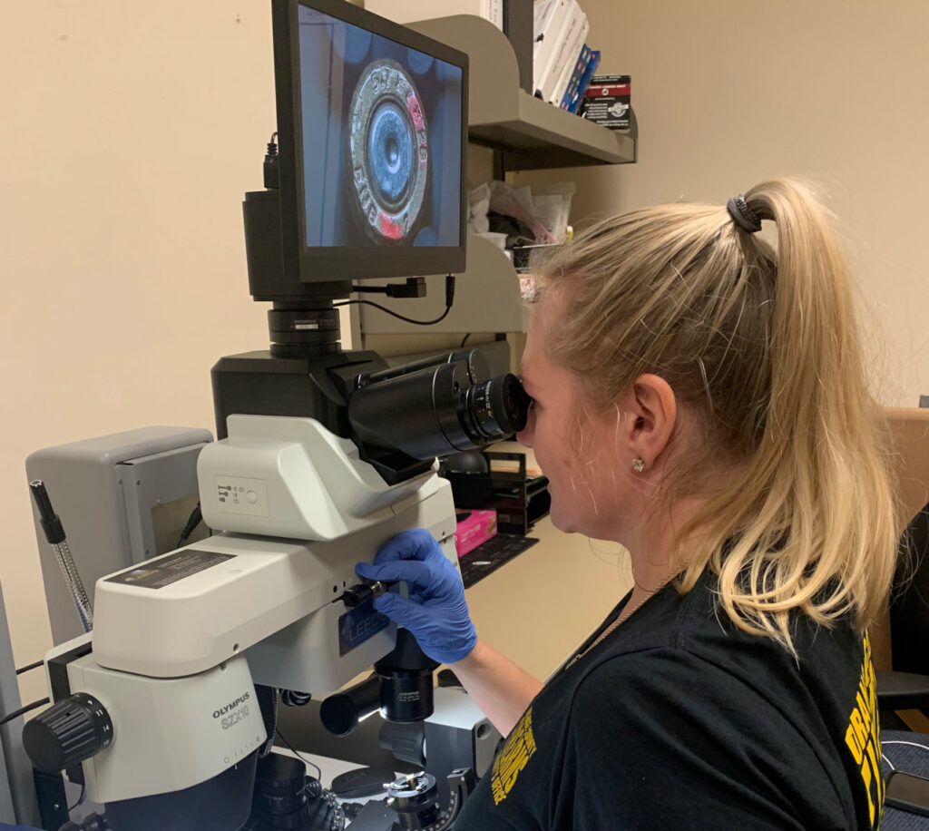 A forensics specialist using a microscope