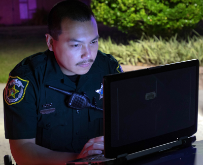 A deputy on a laptop on scene
