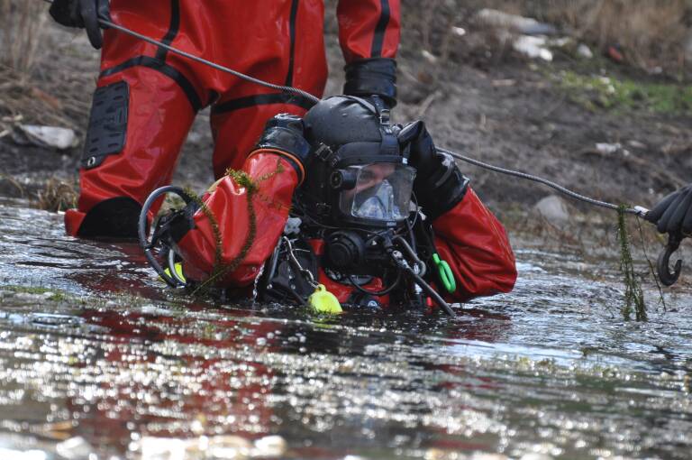 The dive team submerging into murky water